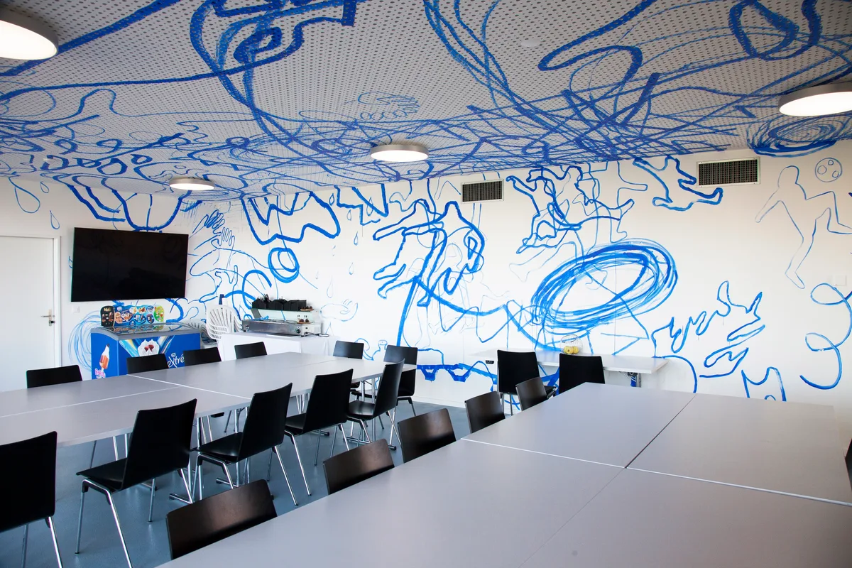 Man sieht Kunst an einer Wand in einem Raum mit Stühlen.